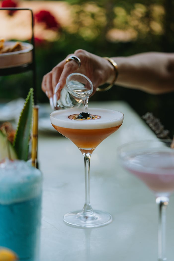 Detailed shot of liquor being poured into a cocktail with garnish.